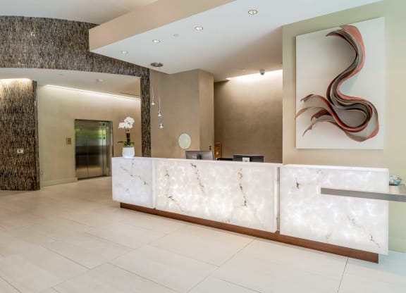 a reception desk in a hotel lobby with a painting on the wall at The Acadia at Metropolitan Park, Arlington, VA